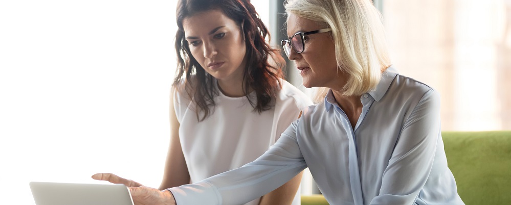 Serious middle aged executive manager explaining colleague online work together pointing at laptop, mature older financial advisor insurer or bank worker making offer to client, advisory services